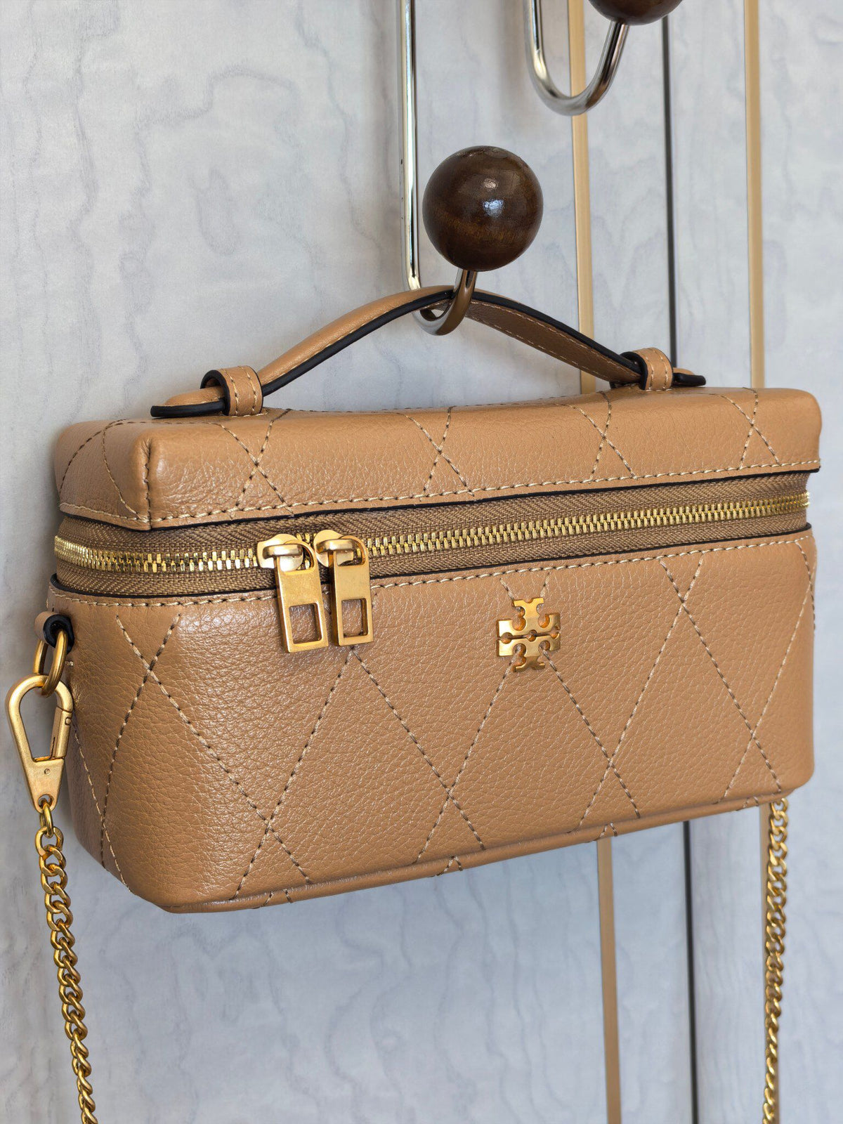 Apricot TORY BURCH KIRA DIAMOND QUILT CHARM EAST-WEST VANITY CASE diamond box bag is made of quilted cowhide with iconic double T metal logo, simple yet recognizable. The chain shoulder strap can be carried diagonally or carried on one shoulder, flexible