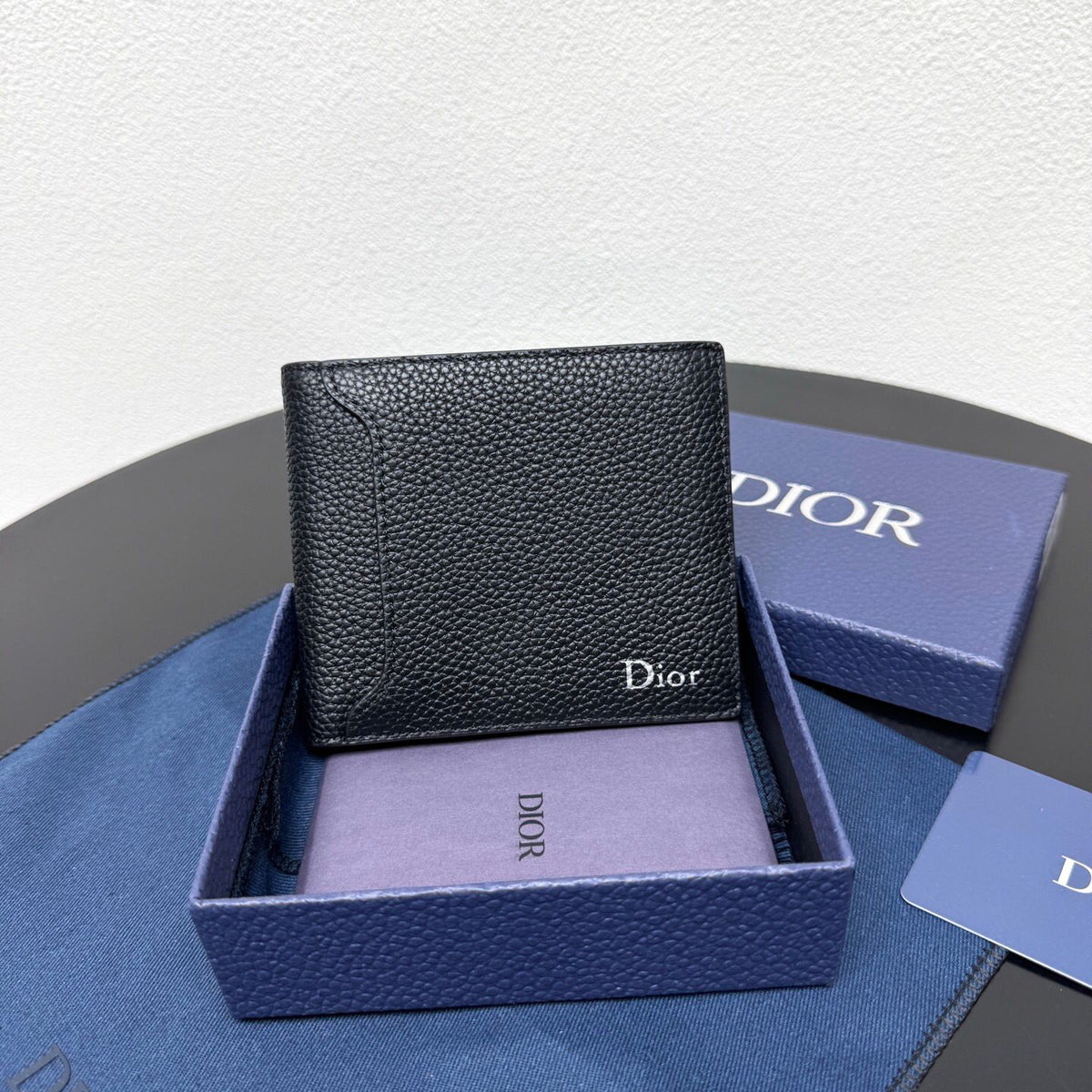 This bifold wallet is a compact accessory. Sophisticated and elegant. Crafted from grained calfskin. CD logo on the front. Features a double cash compartment on the interior. Two bill pockets and eight card slots. Bifold style fits easily into a pocket