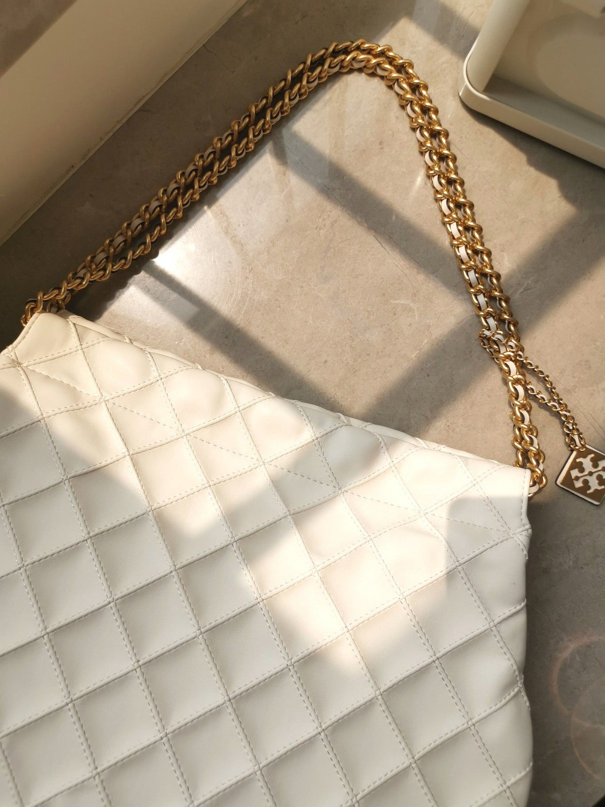 TORY BURCH shopping bag is carefully crafted with soft leather and infused with diamond shaped pleats for a soft and personalized look. The bag size is 363011