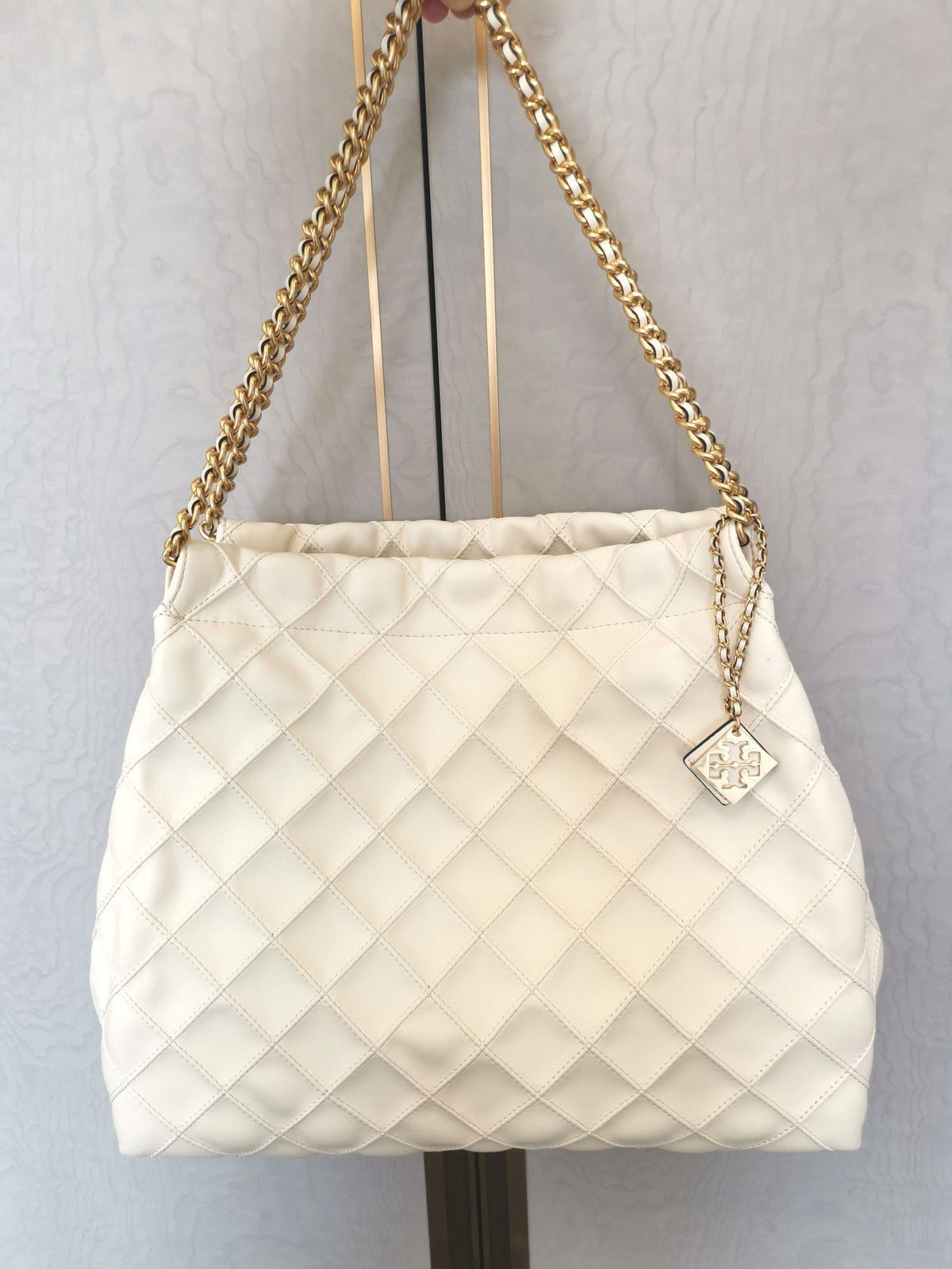 TORY BURCH shopping bag is carefully crafted with soft leather and infused with diamond shaped pleats for a soft and personalized look. The bag size is 363011
