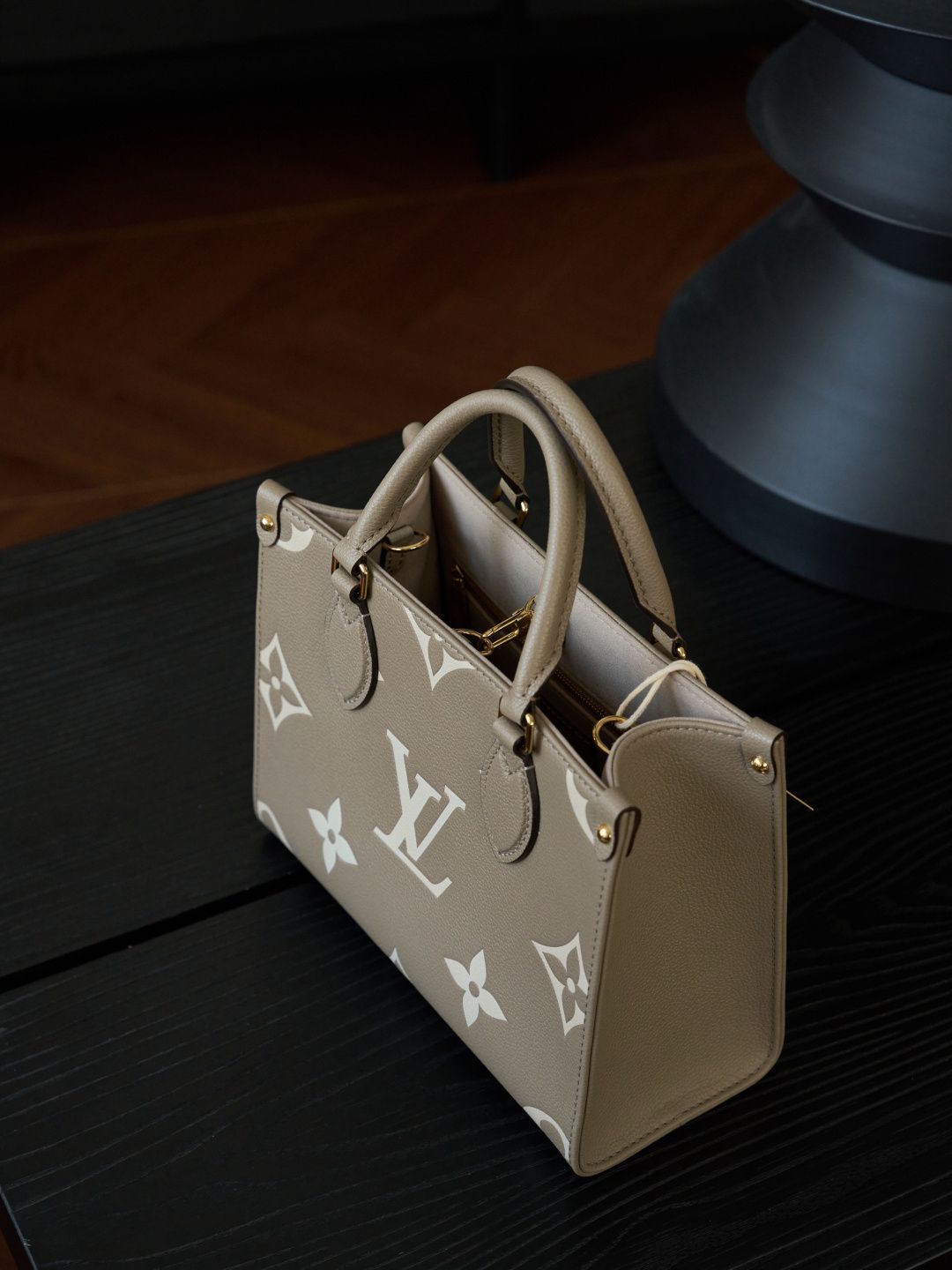 ONTHEGO Small Handbag M45779 This OnTheGo Small Tote Bag draws inspiration from the Sac Plat handbag, which was born in 1968, and incorporates Monogram Empreinte leather with Medium Bicolor Monogram embossing for a slightly smaller size. The original