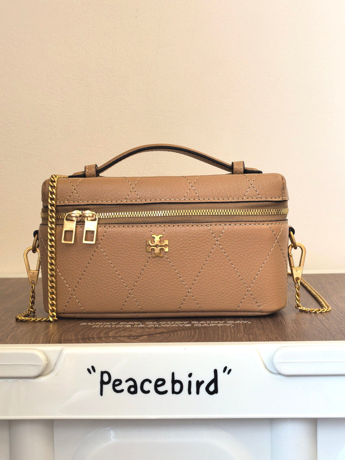 Apricot TORY BURCH KIRA DIAMOND QUILT CHARM EAST-WEST VANITY CASE diamond box bag is made of quilted cowhide with iconic double T metal logo, simple yet recognizable. The chain shoulder strap can be carried diagonally or carried on one shoulder, flexible