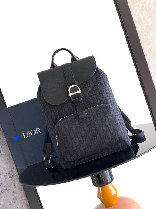 The Heritage Saddle Flap Backpack features a sleek, original design that accentuates your saddle style. Crafted from black Oblique printed fabric, accented with tonal grained calf leather details for added style. A spacious compartment under the saddle