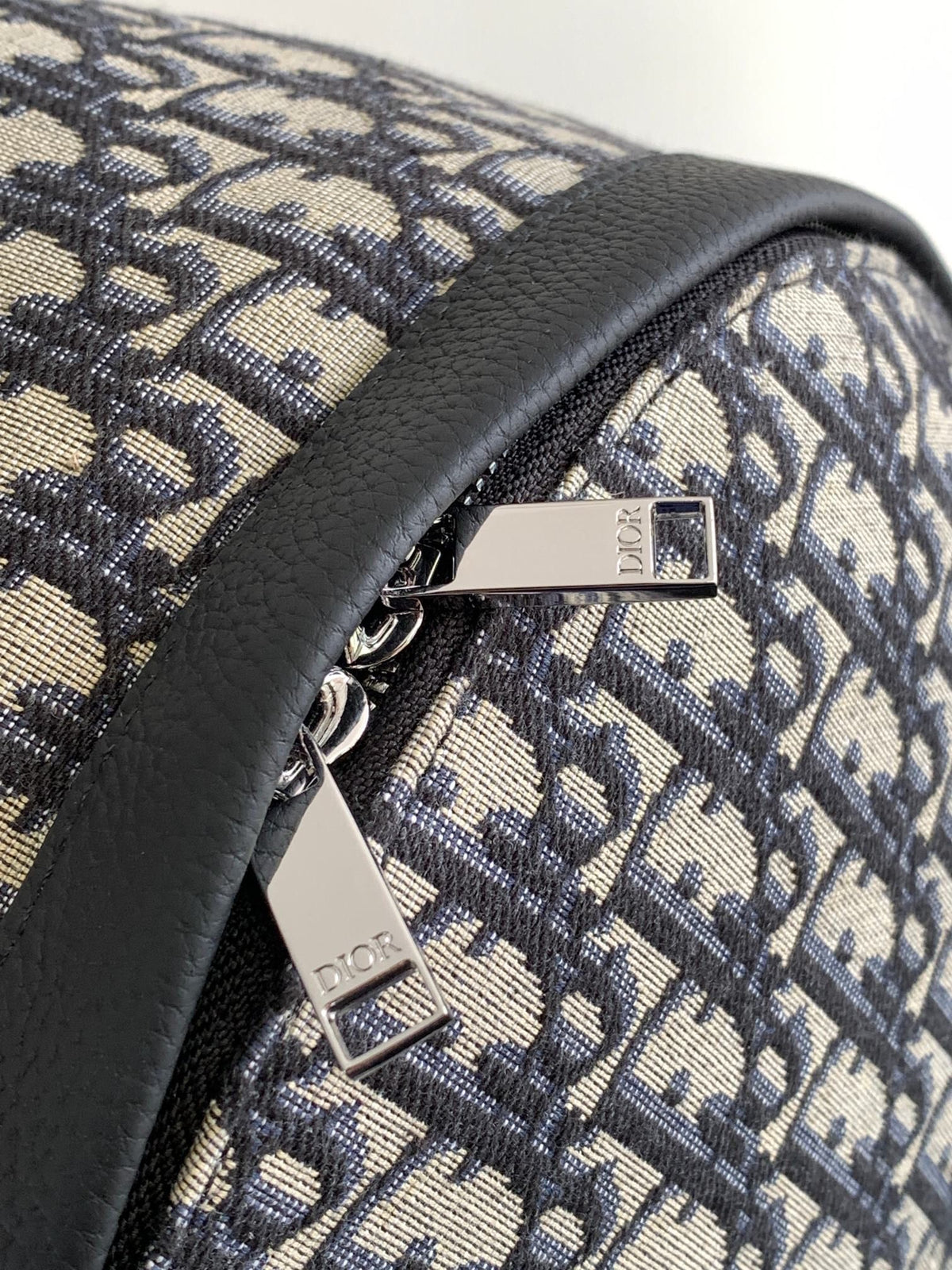 Under the small black lettering. This Rider backpack has a simple silhouette. The classic collegiate style is full of energy. Inspired by the Dior men's collection. Reinterpreted in beige and blue jacquard fabrics. Oblique print throughout. Continuing
