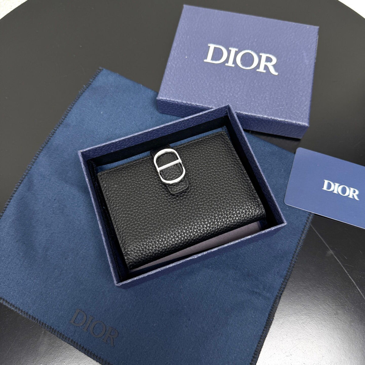 This vertical bifold card holder is elegant and practical. It is crafted from grained cow leather. It is decorated with the CD logo on the front. It has three card slots on each side and two receipt pockets. It is exquisite and elegant. It can be easily