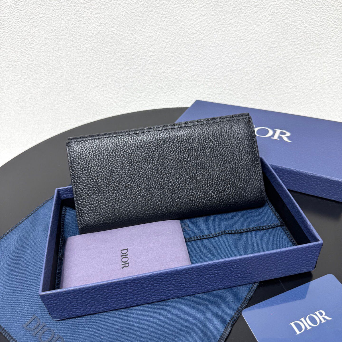 Stylish and functional, this vertical bi-fold wallet is crafted from black grained cow leather. Vertical bi-fold design. CD logo on front for added style. Features five cash compartments, 16 card slots and a zippered coin compartment. Long vertical design