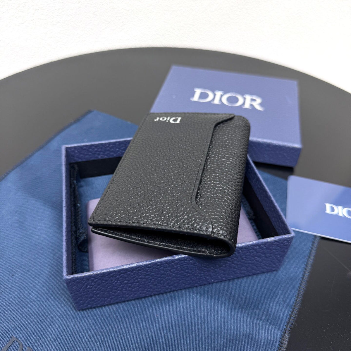 This vertical bifold card holder is elegant and practical. It is crafted from grained cow leather. It is decorated with the CD logo on the front. It has three card slots on each side and two receipt pockets. It is exquisite and elegant. It can be easily