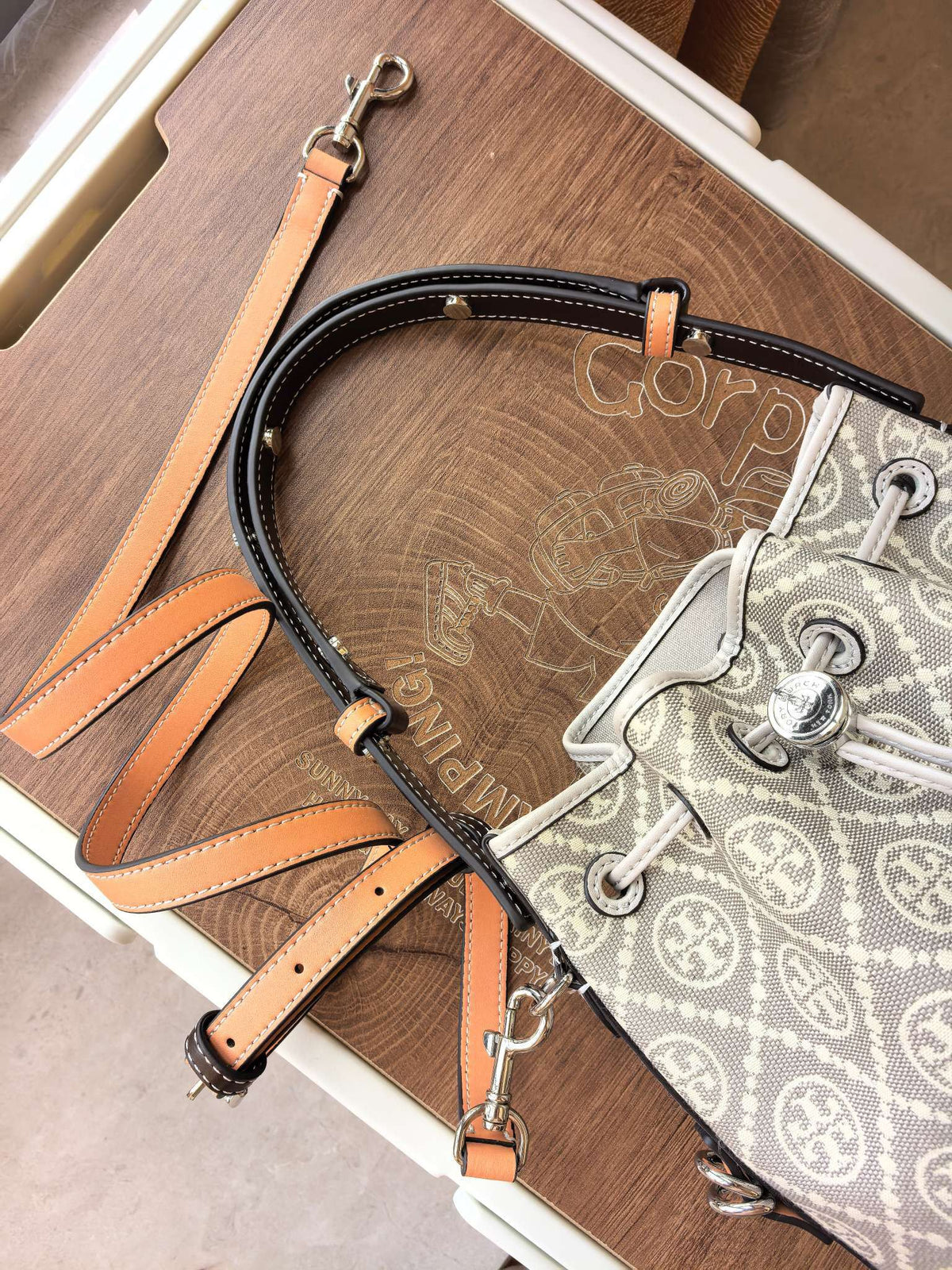 ToryBurch's new 1615A vintage water bucket bag features a classic TMonogram pattern fused with jacquard fabric, creating a charming and timeless style. This bucket bag is adorned with delicate leather trim, a top handle, and a detachable diagonal strap