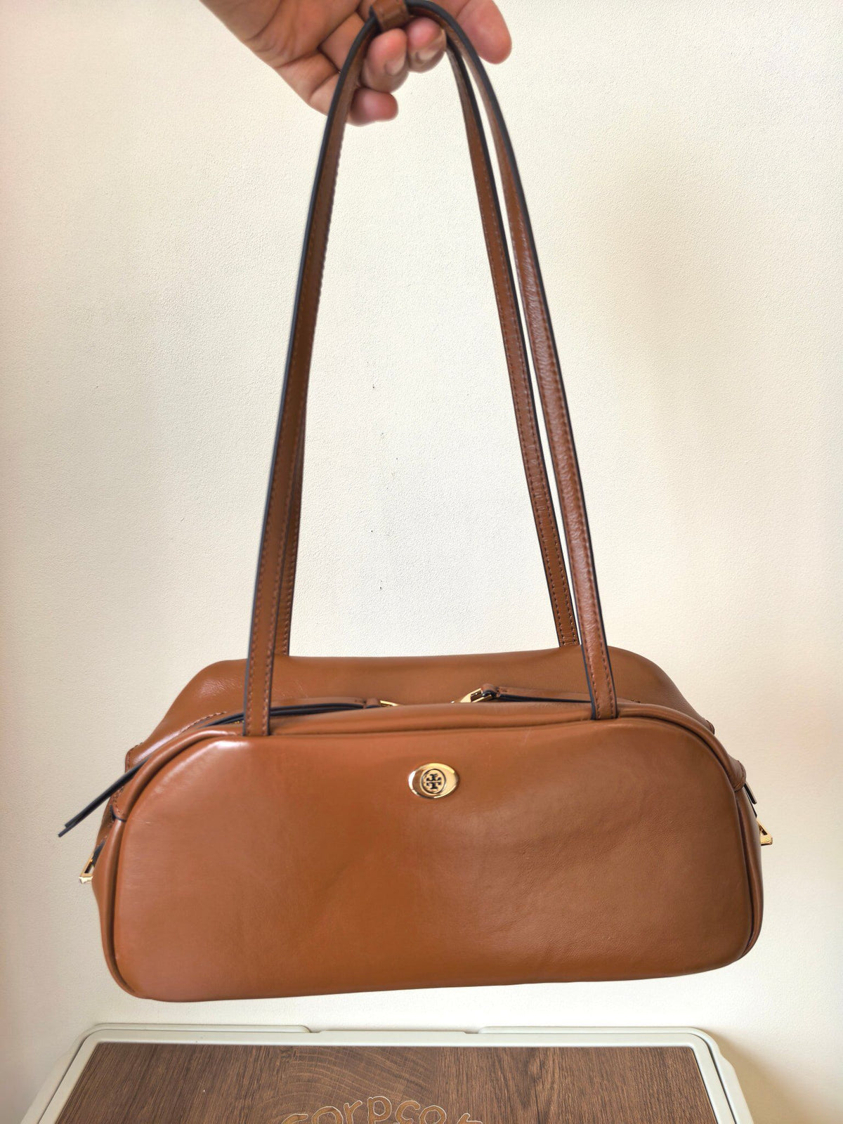 The new TORY BURCH ROBINSON SATCHEL bowling bag is made of oil wax cowhide material, which has a delicate, durable, simple and atmospheric feel. The front brand metal logo is highly recognizable and durable. The bag has a round shape and a large capacity
