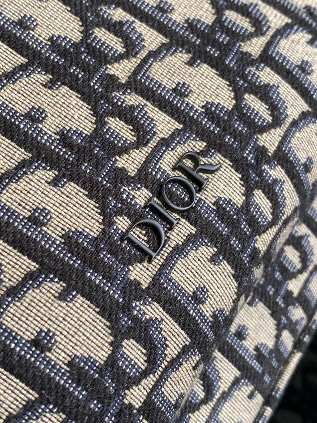 Under the small black lettering. This Rider backpack has a simple silhouette. The classic collegiate style is full of energy. Inspired by the Dior men's collection. Reinterpreted in beige and blue jacquard fabrics. Oblique print throughout. Continuing