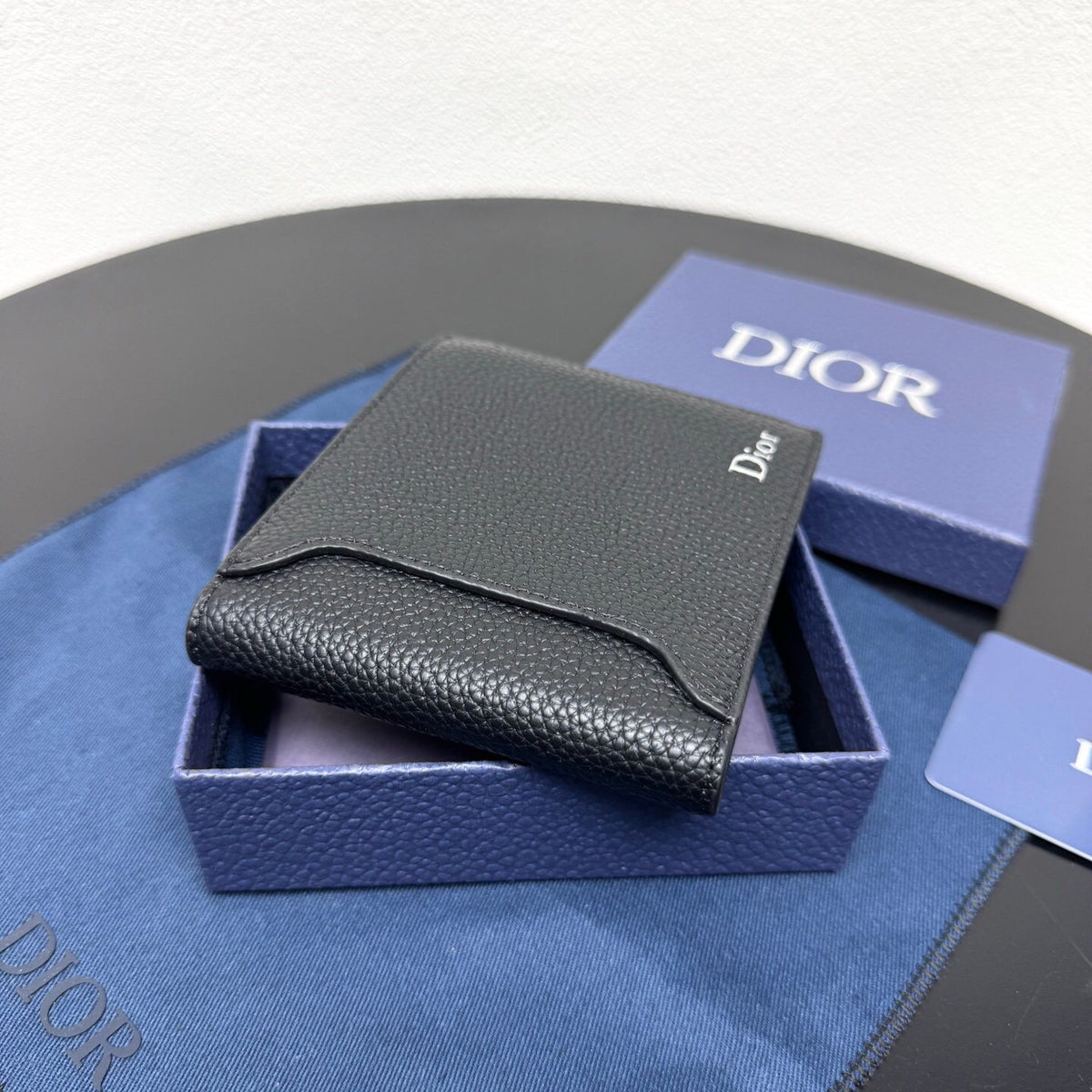 This bifold wallet is a compact accessory. Sophisticated and elegant. Crafted from grained calfskin. CD logo on the front. Features a double cash compartment on the interior. Two bill pockets and eight card slots. Bifold style fits easily into a pocket