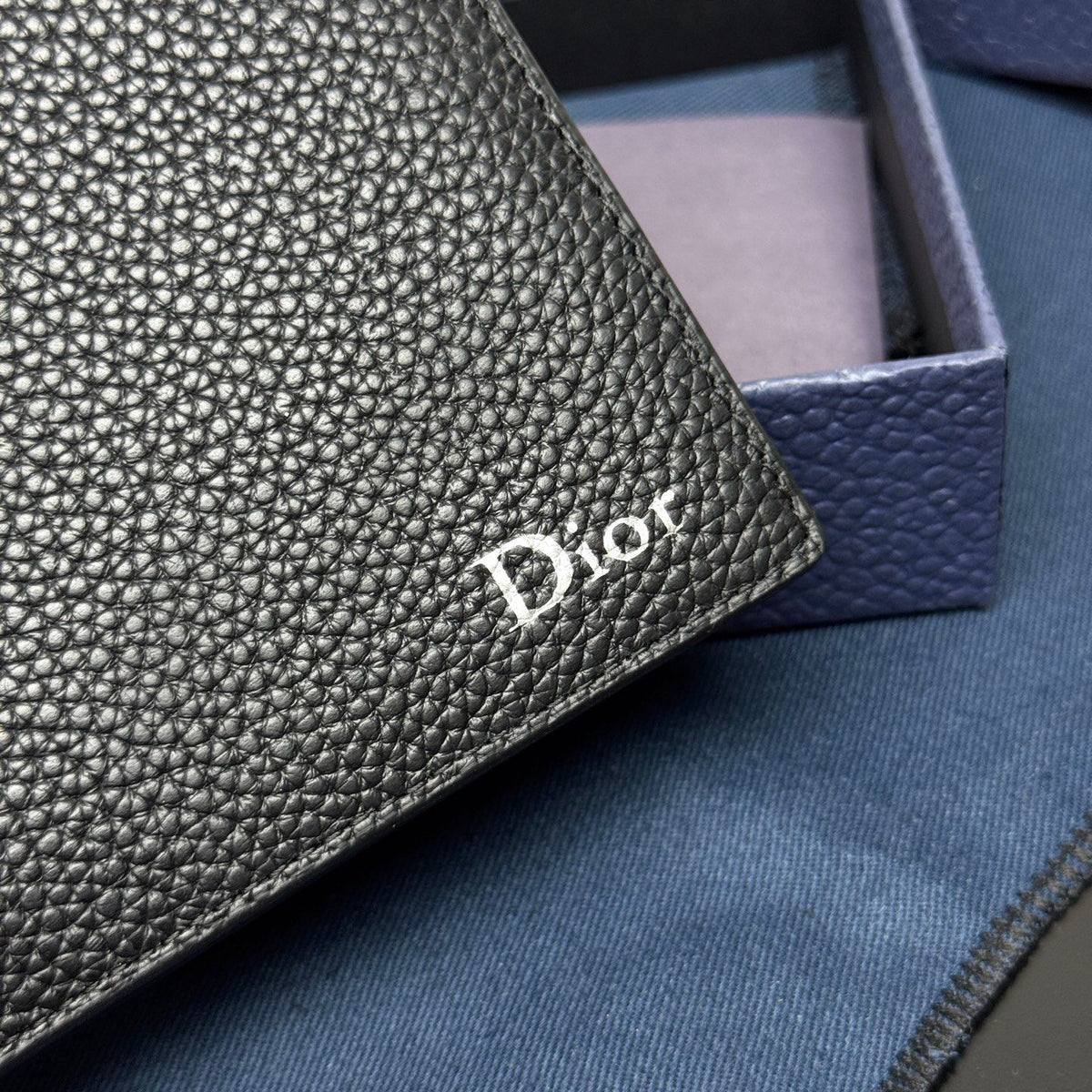 This bifold wallet is a compact accessory. Sophisticated and elegant. Crafted from grained calfskin. CD logo on the front. Features a double cash compartment on the interior. Two bill pockets and eight card slots. Bifold style fits easily into a pocket