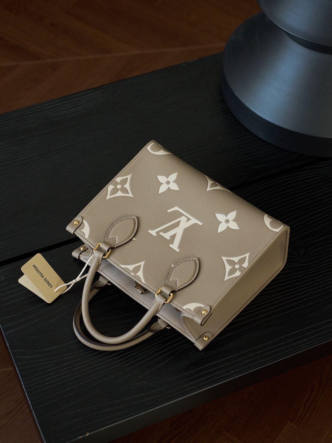 ONTHEGO Small Handbag M45779 This OnTheGo Small Tote Bag draws inspiration from the Sac Plat handbag, which was born in 1968, and incorporates Monogram Empreinte leather with Medium Bicolor Monogram embossing for a slightly smaller size. The original