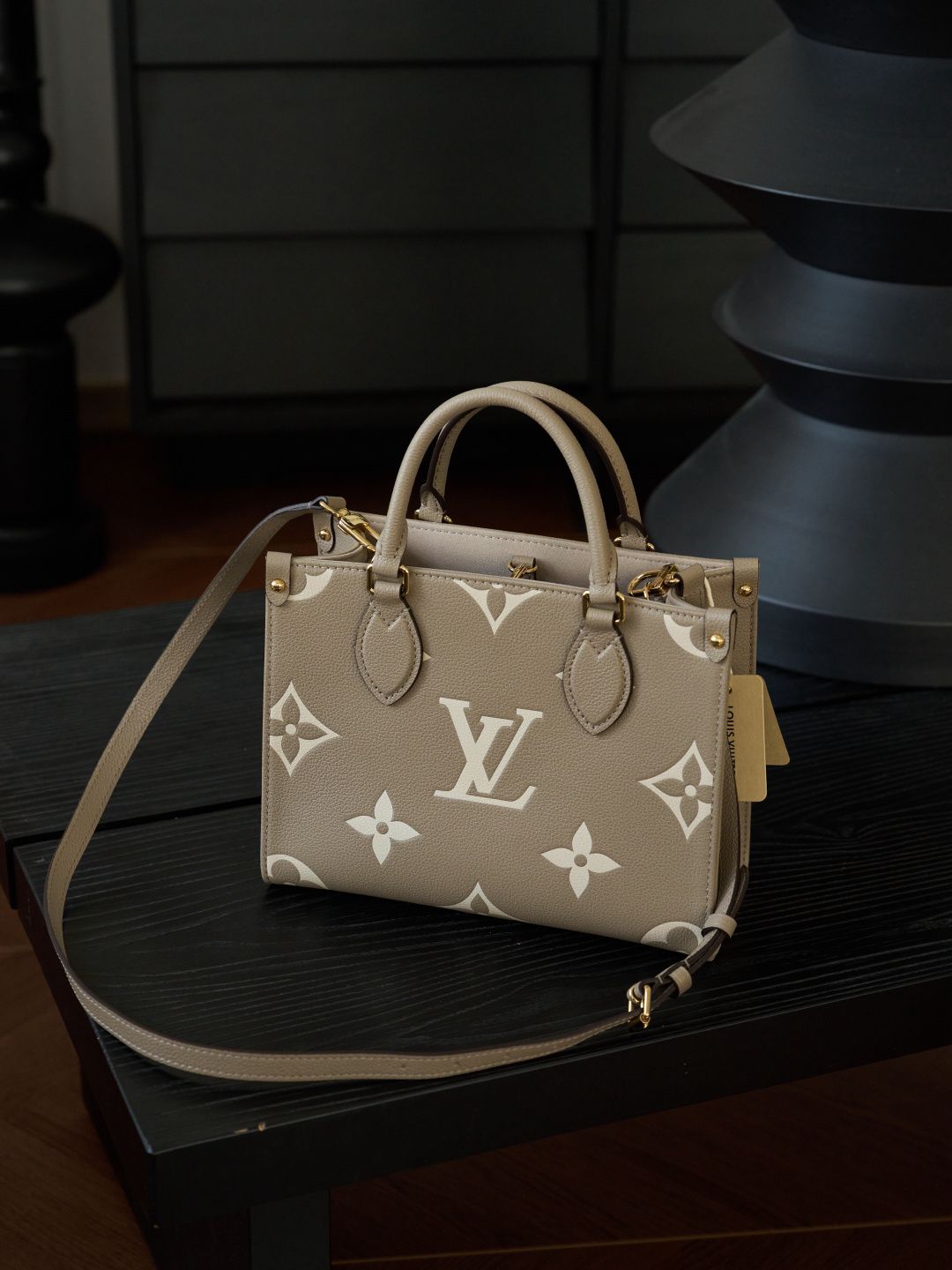 ONTHEGO Small Handbag M45779 This OnTheGo Small Tote Bag draws inspiration from the Sac Plat handbag, which was born in 1968, and incorporates Monogram Empreinte leather with Medium Bicolor Monogram embossing for a slightly smaller size. The original