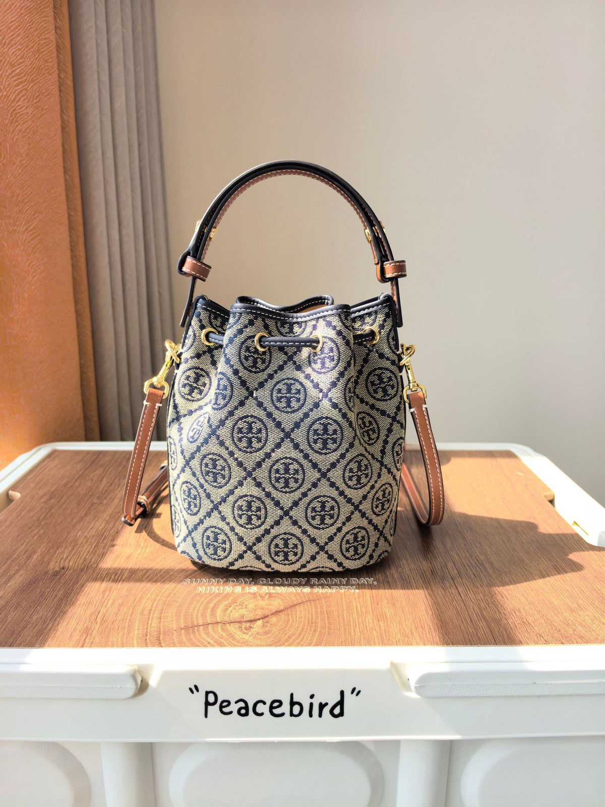 ToryBurch's new 1616A vintage water bucket bag features a classic TMonogram pattern fused with jacquard fabric, creating a charming and timeless style. This mini water bucket bag is adorned with delicate leather trim, a top handle, and a detachable diagon