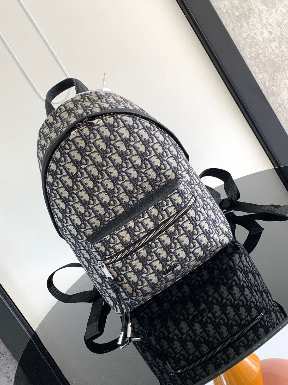 Under the small black lettering. This Rider backpack has a simple silhouette. The classic collegiate style is full of energy. Inspired by the Dior men's collection. Reinterpreted in beige and blue jacquard fabrics. Oblique print throughout. Continuing