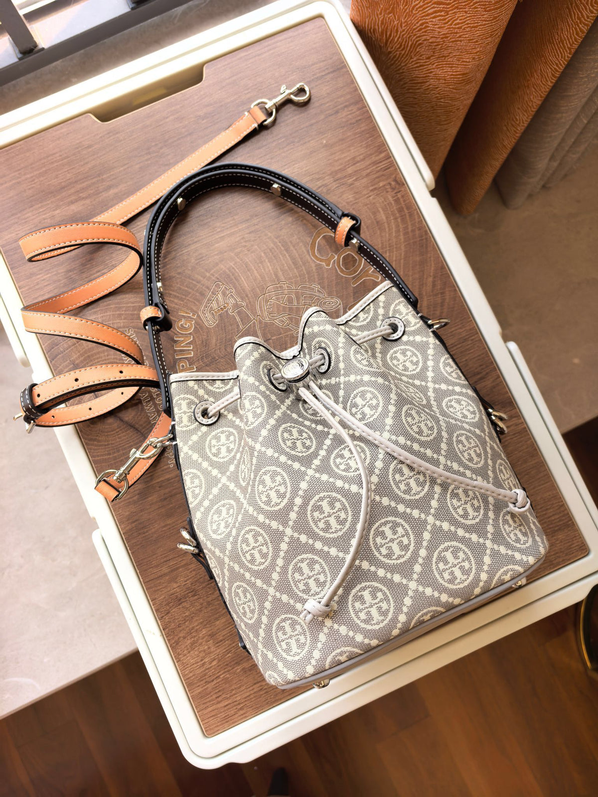 ToryBurch's new 1615A vintage water bucket bag features a classic TMonogram pattern fused with jacquard fabric, creating a charming and timeless style. This bucket bag is adorned with delicate leather trim, a top handle, and a detachable diagonal strap