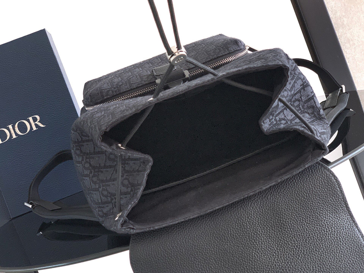 The Heritage Saddle Flap Backpack features a sleek, original design that accentuates your saddle style. Crafted from black Oblique printed fabric, accented with tonal grained calf leather details for added style. A spacious compartment under the saddle