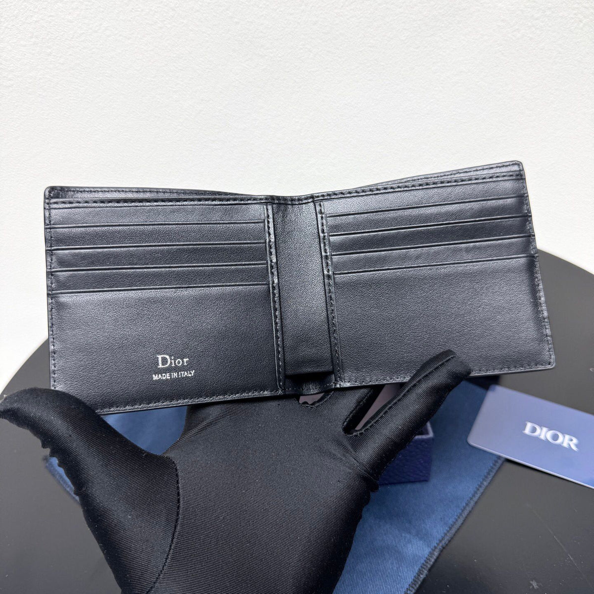 This bifold wallet is a compact accessory. Sophisticated and elegant. Crafted from grained calfskin. CD logo on the front. Features a double cash compartment on the interior. Two bill pockets and eight card slots. Bifold style fits easily into a pocket