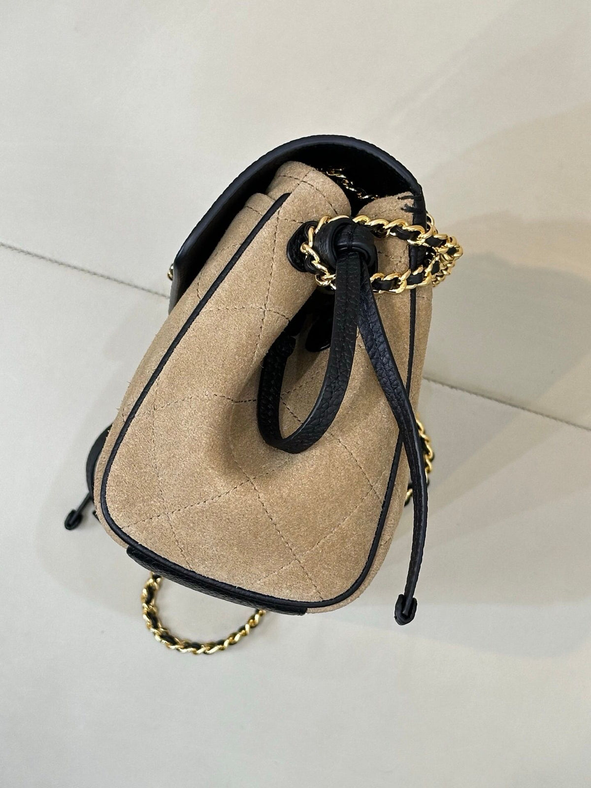 The main body of the apricot bag is made of fine khaki suede. The surface layer has even and soft fluff, with a matte matte texture. It has a retro and old atmosphere. The upper cover is spliced with black grained cowhide. The collision of soft and