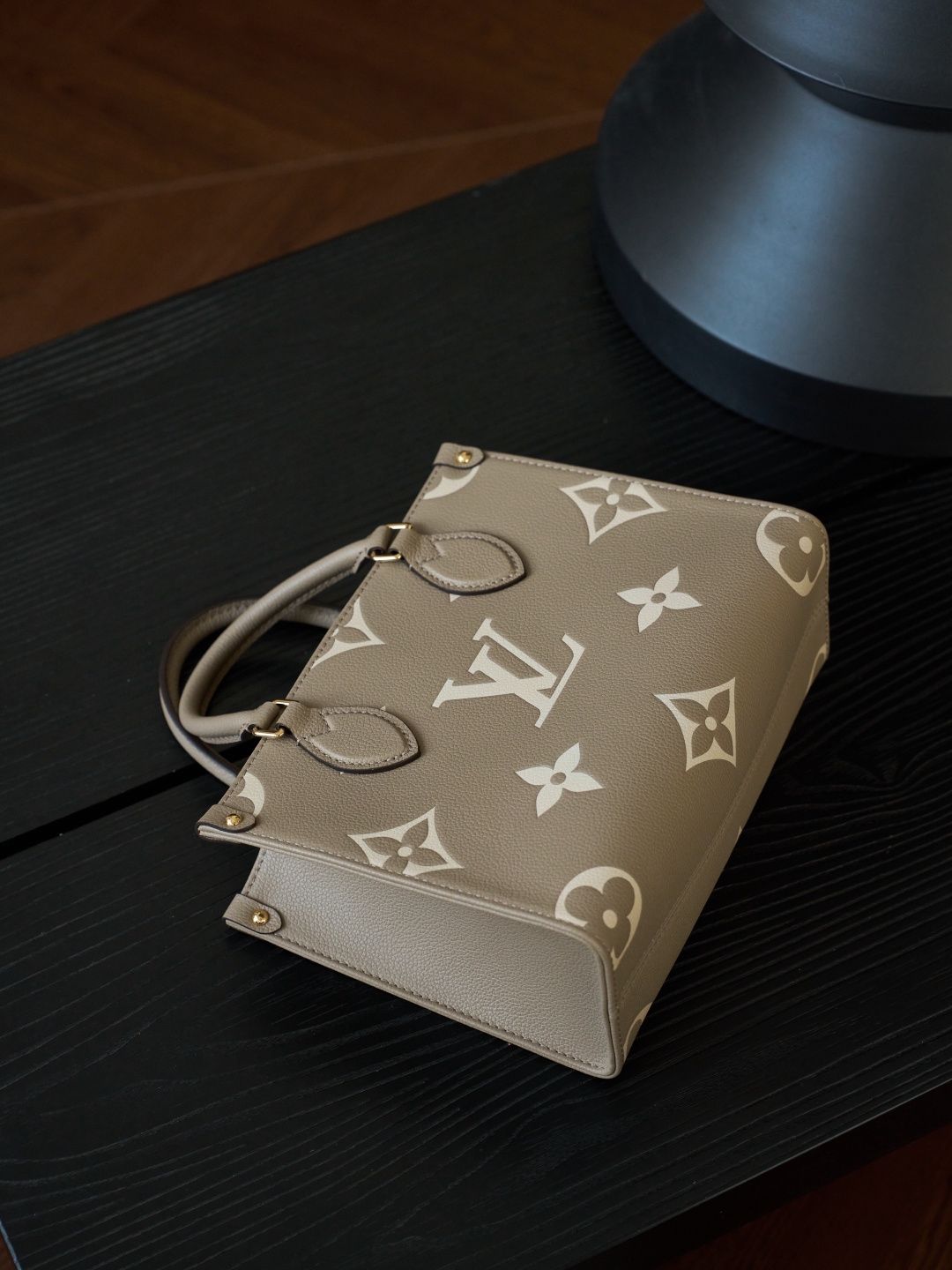 ONTHEGO Small Handbag M45779 This OnTheGo Small Tote Bag draws inspiration from the Sac Plat handbag, which was born in 1968, and incorporates Monogram Empreinte leather with Medium Bicolor Monogram embossing for a slightly smaller size. The original