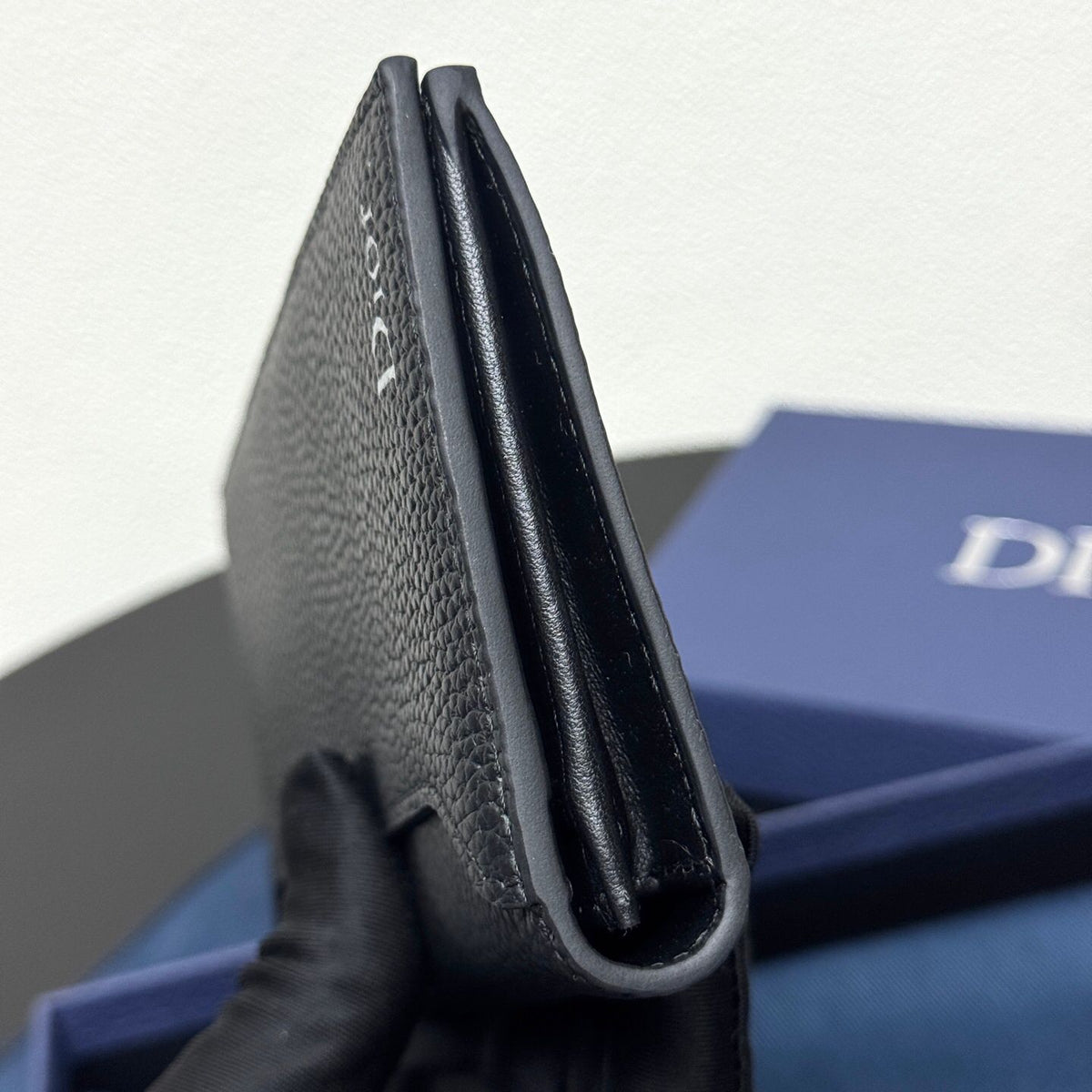 Stylish and functional, this vertical bi-fold wallet is crafted from black grained cow leather. Vertical bi-fold design. CD logo on front for added style. Features five cash compartments, 16 card slots and a zippered coin compartment. Long vertical design