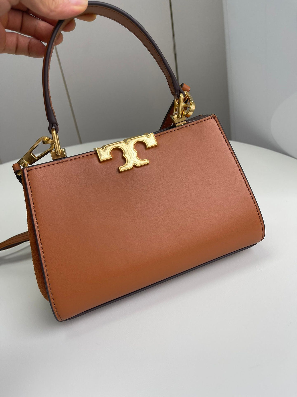 Number 086, TORY BURCH. New Eleanor leather handbag with exquisite suede trim. The bag has a clean and crisp body, and the iconic double T logo is three-dimensional and eye-catching. Exquisite craftsmanship. It can be lifted with a handle or removed