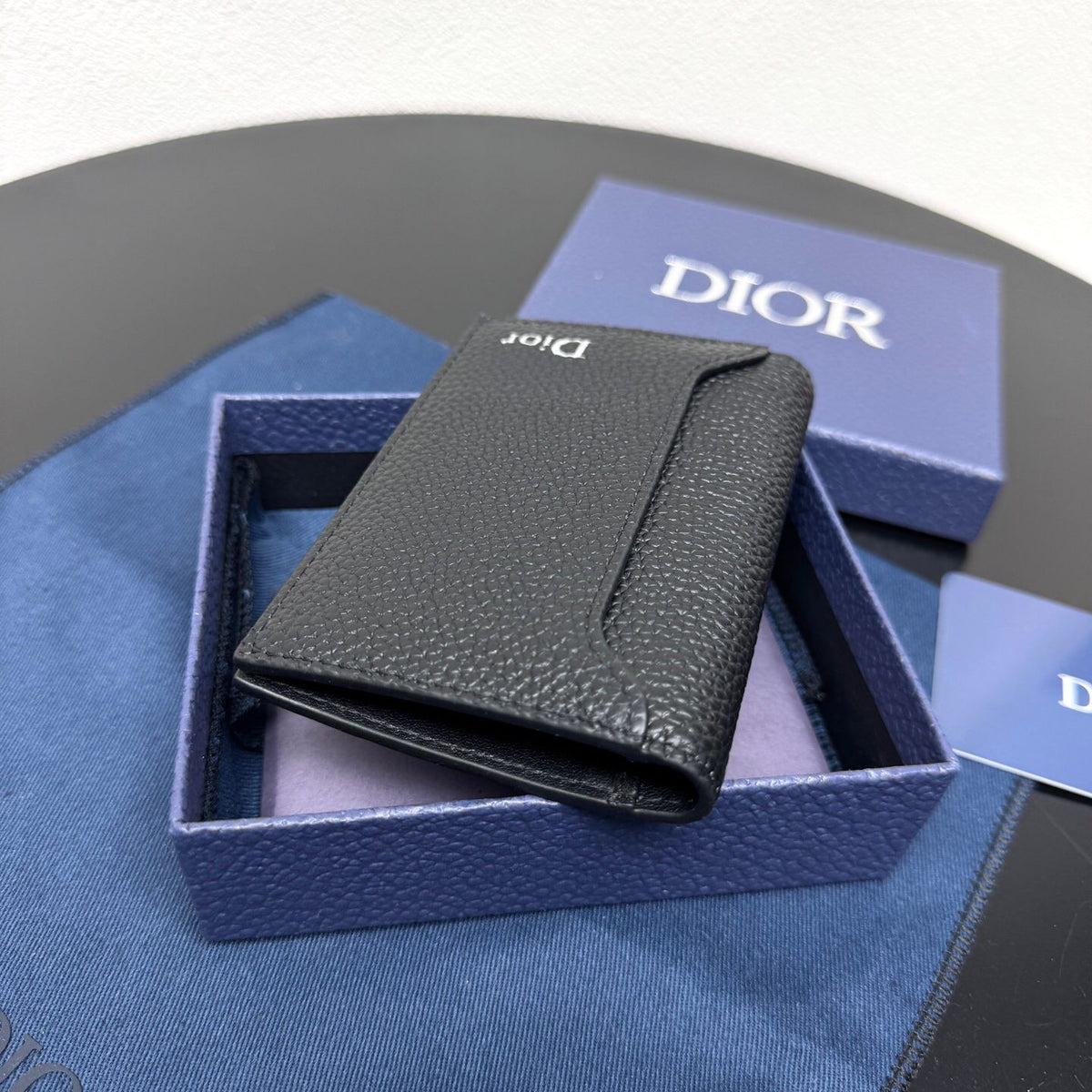 This vertical bifold card holder is elegant and practical. It is crafted from grained cow leather. It is decorated with the CD logo on the front. It has three card slots on each side and two receipt pockets. It is exquisite and elegant. It can be easily