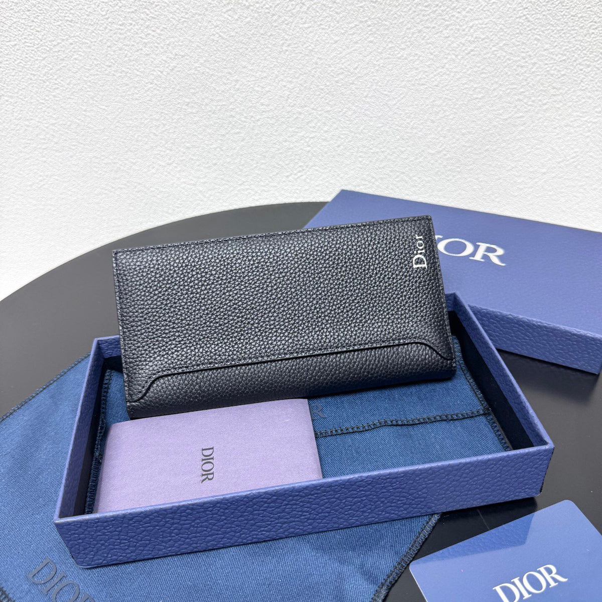 Stylish and functional, this vertical bi-fold wallet is crafted from black grained cow leather. Vertical bi-fold design. CD logo on front for added style. Features five cash compartments, 16 card slots and a zippered coin compartment. Long vertical design
