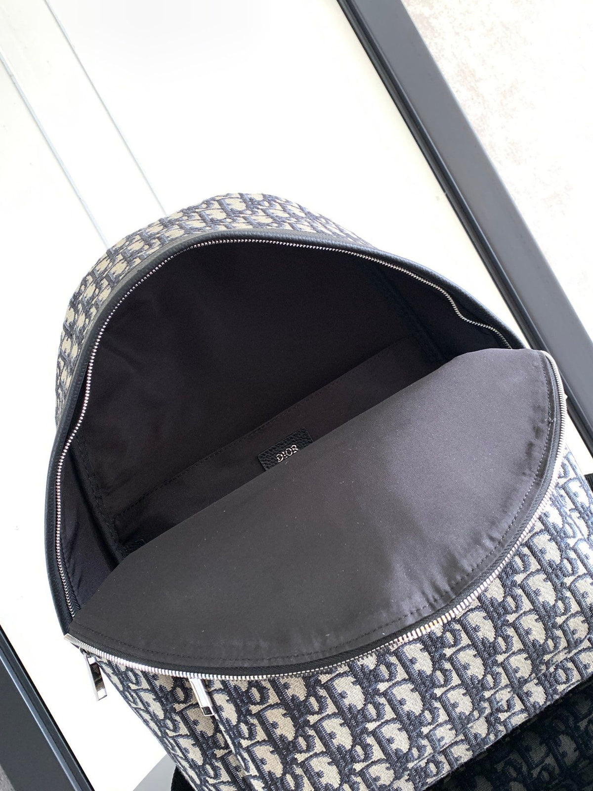 Large black text label. Top original order. This Rider backpack has a simple silhouette. The classic collegiate style is full of vitality. It is fashionable and modern. It is carefully made of beige and black jacquard fabrics and decorated with Oblique