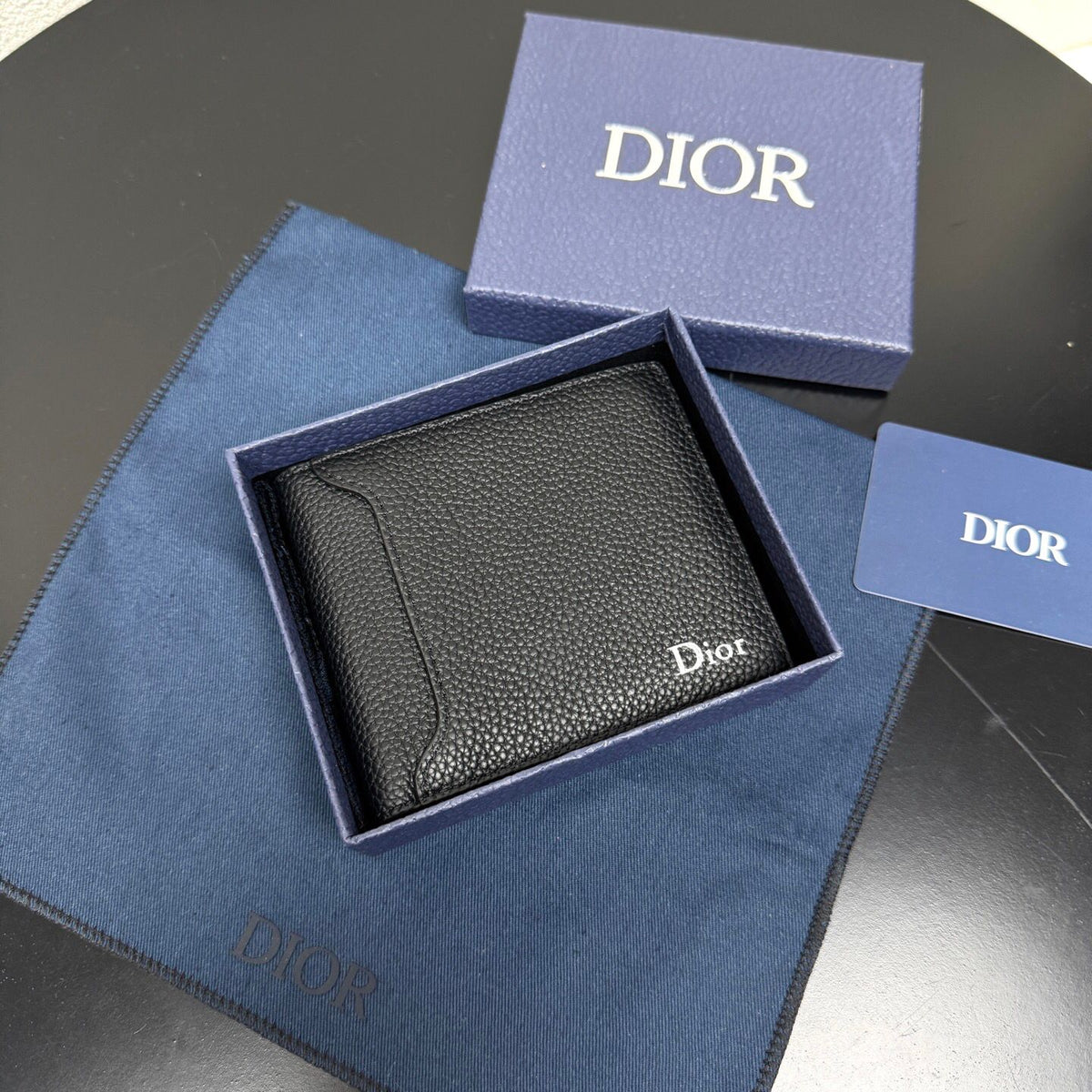 This bifold wallet is a compact accessory. Sophisticated and elegant. Crafted from grained calfskin. CD logo on the front. Features a double cash compartment on the interior. Two bill pockets and eight card slots. Bifold style fits easily into a pocket