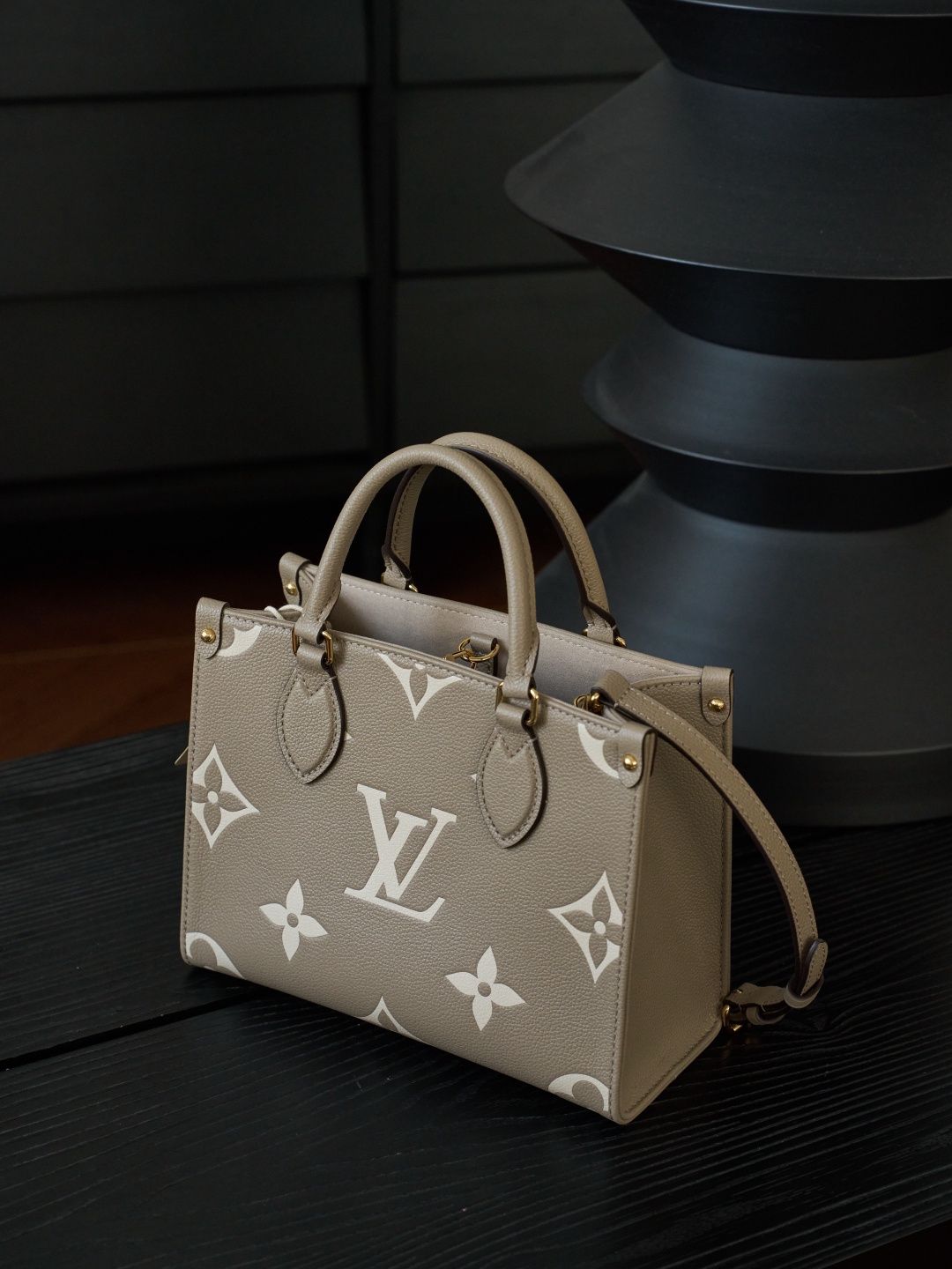ONTHEGO Small Handbag M45779 This OnTheGo Small Tote Bag draws inspiration from the Sac Plat handbag, which was born in 1968, and incorporates Monogram Empreinte leather with Medium Bicolor Monogram embossing for a slightly smaller size. The original