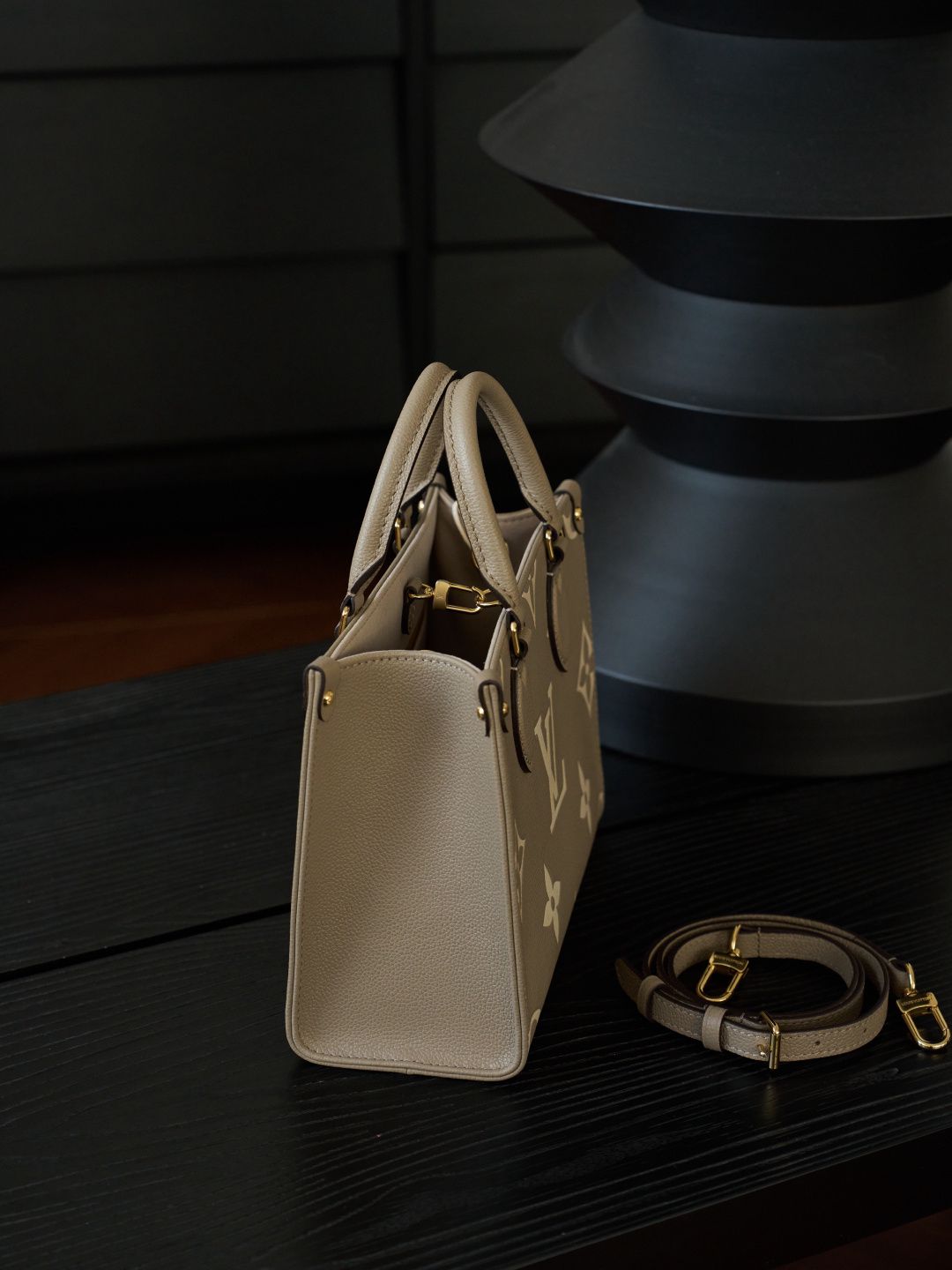 ONTHEGO Small Handbag M45779 This OnTheGo Small Tote Bag draws inspiration from the Sac Plat handbag, which was born in 1968, and incorporates Monogram Empreinte leather with Medium Bicolor Monogram embossing for a slightly smaller size. The original