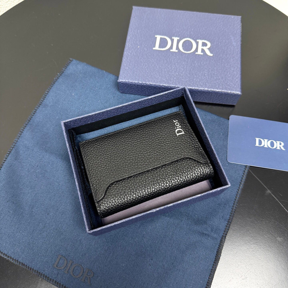 This vertical bifold card holder is elegant and practical. It is crafted from grained cow leather. It is decorated with the CD logo on the front. It has three card slots on each side and two receipt pockets. It is exquisite and elegant. It can be easily