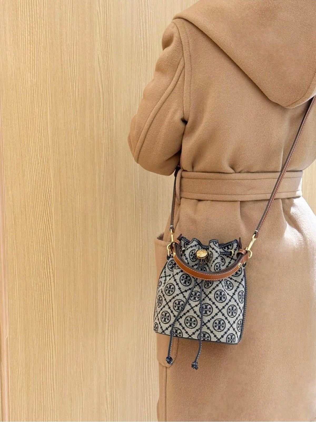ToryBurch's new 1616A vintage water bucket bag features a classic TMonogram pattern fused with jacquard fabric, creating a charming and timeless style. This mini water bucket bag is adorned with delicate leather trim, a top handle, and a detachable diagon