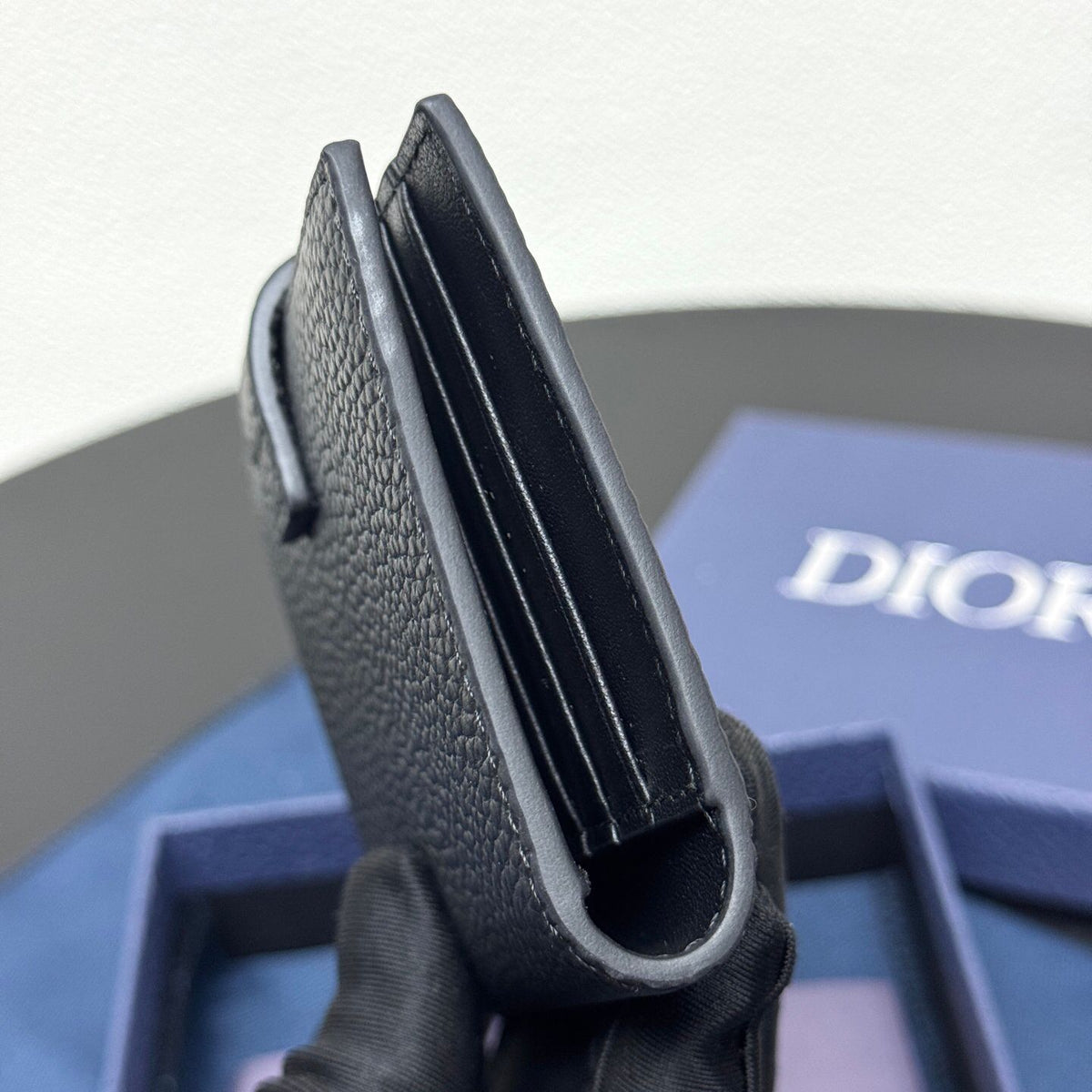 This vertical bifold card holder is elegant and practical. It is crafted from grained cow leather. It is decorated with the CD logo on the front. It has three card slots on each side and two receipt pockets. It is exquisite and elegant. It can be easily