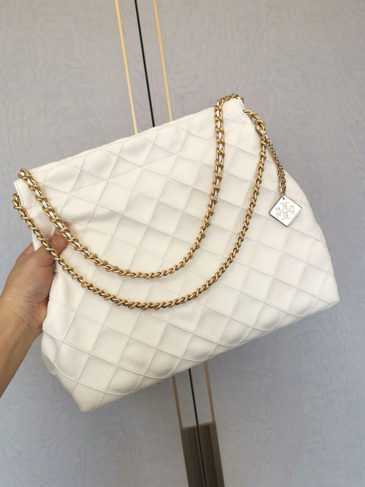 TORY BURCH shopping bag is carefully crafted with soft leather and infused with diamond shaped pleats for a soft and personalized look. The bag size is 363011