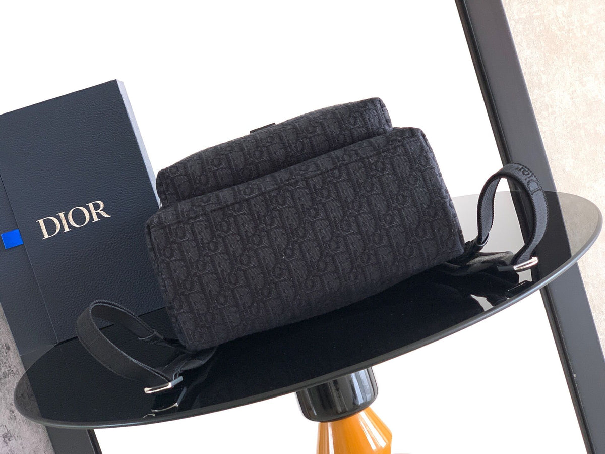 The Heritage Saddle Flap Backpack features a sleek, original design that accentuates your saddle style. Crafted from black Oblique printed fabric, accented with tonal grained calf leather details for added style. A spacious compartment under the saddle